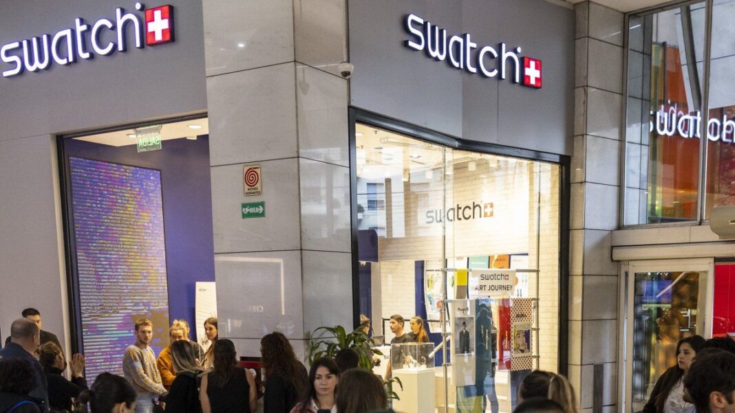 Fila de personas esperando fuera de la tienda Swatch en Alto Palermo Shopping para el lanzamiento de la colección Omega x Swatch.