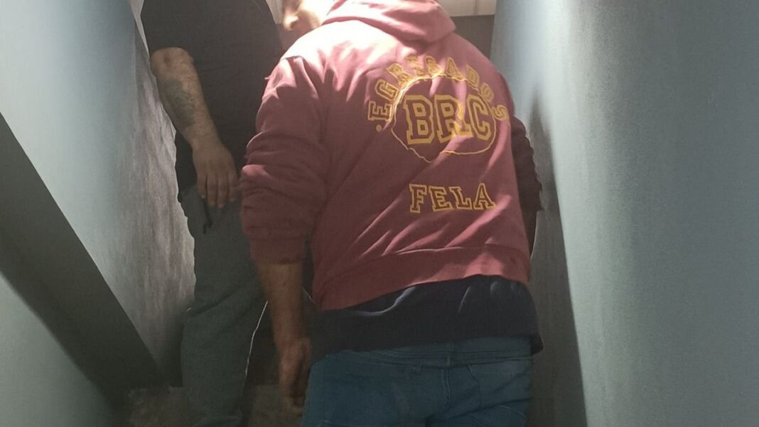Albañil usando un buzo de egresados con la leyenda Fela en la espalda, en Villa Gobernador Gálvez