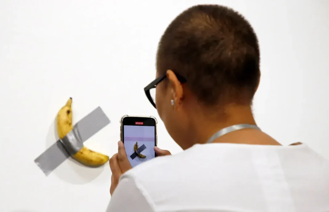 Banana adherida a una pared con cinta adhesiva plateada, parte de la obra Comedian de Maurizio Cattelan