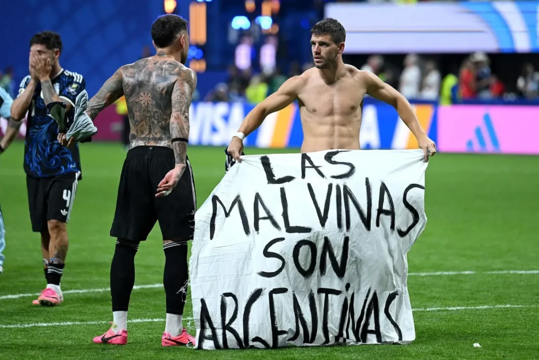 Jugadores argentinos colocan bandera con la leyenda Las Malvinas son argentinas en el césped del estadio