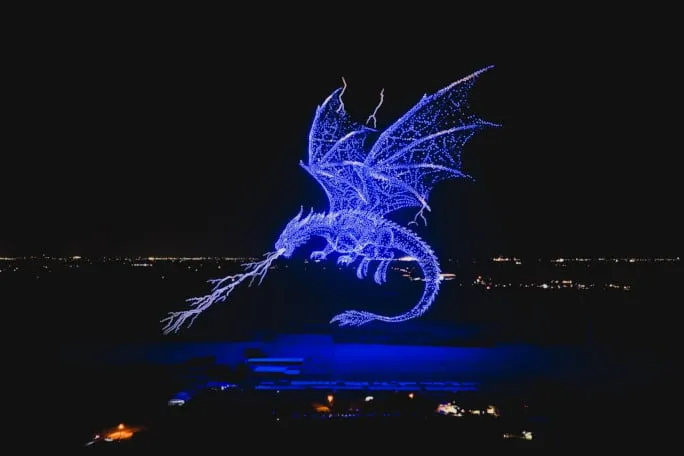 Formación de miles de drones iluminados simulando un dragón gigante en el cielo nocturno de Texas